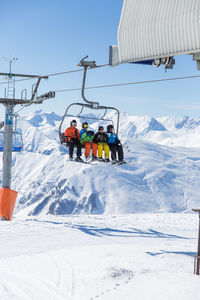 People in ski lift against sky during winter