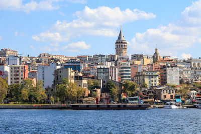 Buildings at waterfront against cloudy sky