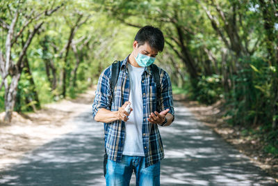 Young man standing on road in forest