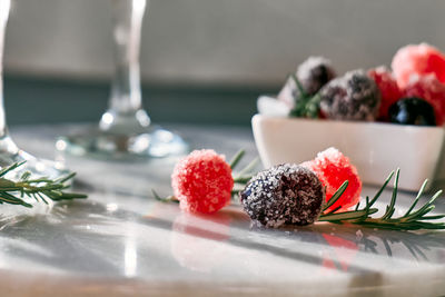 Christmas sweets near wine glasses with cocktail with sparkling wine, rosemary and cherry.