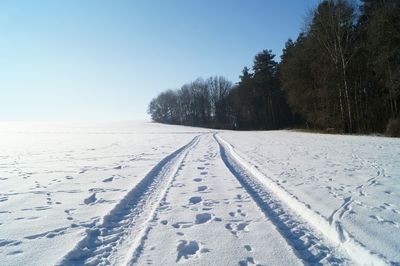 Snow on field against clear sky during winter