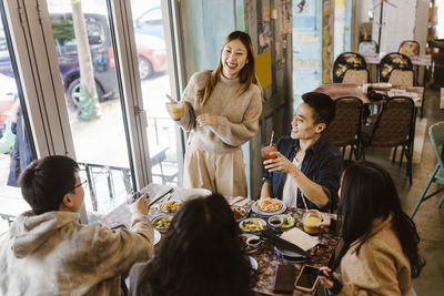 Happy male and female friends enjoying together during lunch at restaurant