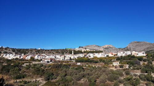 Houses in town against clear blue sky