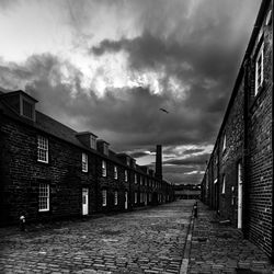 Street amidst buildings against cloudy sky