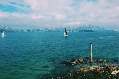 Boats in sea against cloudy sky