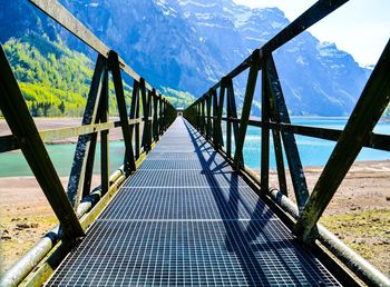 Bridge leading towards mountain against sky