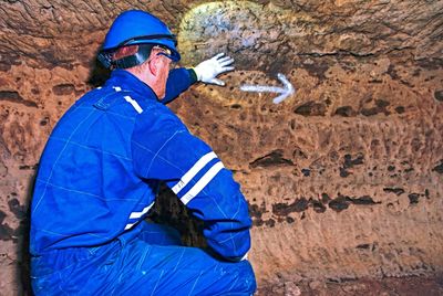 Man underground tunnel. employee in safety suit and helmet in tunnel  built for rich people in war