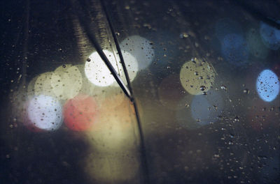 Close-up of wet umbrella against lights at night during monsoon