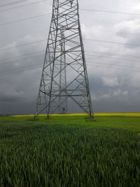 Electricity pylon on field against sky