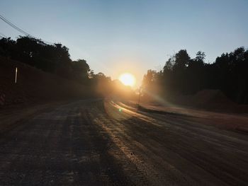 Road amidst trees against sky during sunset