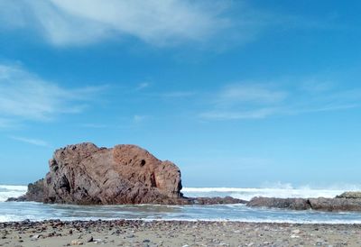 Rock formation on beach against sky