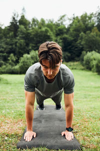 Young man doing push-ups outside on grass during his calisthenics workout