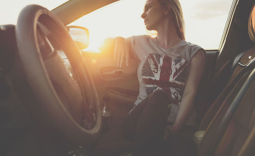 Thoughtful woman sitting in car during sunset