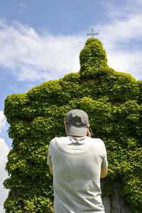 Rear view of man photographing church against sky