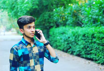 Young man using mobile phone while standing outdoors