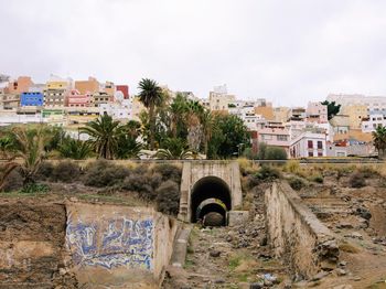 Arch bridge over buildings in city against sky