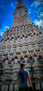 Rear view of man standing outside temple against building