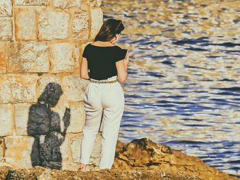 Rear view of woman standing against wall