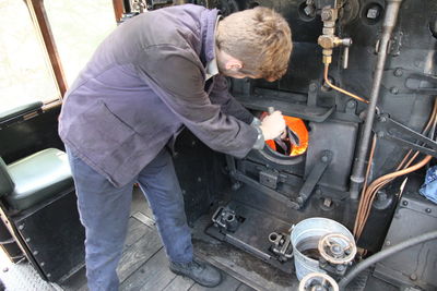 High angle view of train engineer working in steam train