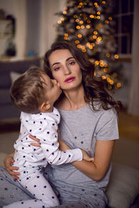 Mom and son sitting in pajamas in a room with a christmas tree