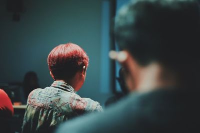 Rear view of red short haired woman sitting in cafe