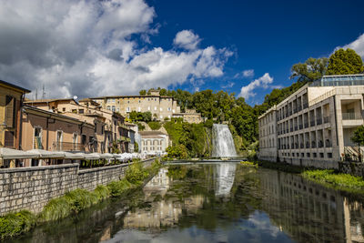 Buildings by river against sky