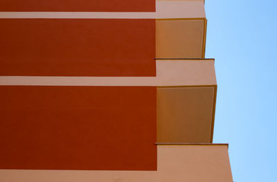 Urban building, residential building facade detail, orange and cream colors plaster, blue sky.