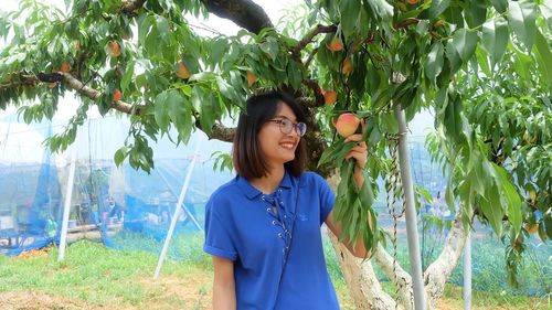 Portrait of young woman standing against trees