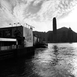 Buildings by river against sky in city