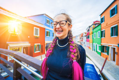 Portrait of young woman standing against buildings