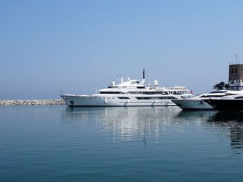 Boats moored on sea against clear blue sky