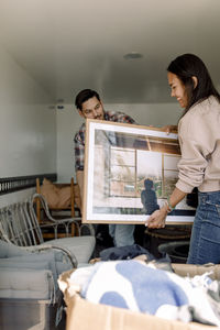 Couple unloading painting from truck while relocating in new house