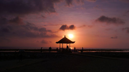 Lifeguard hut on beach against sky during sunset