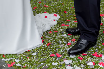 Low section of newlywed standing on confetti at field