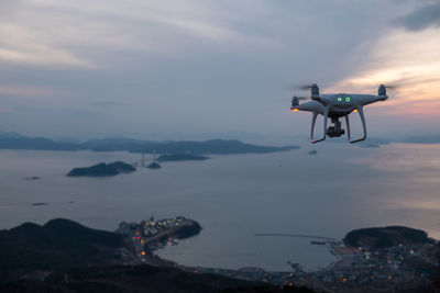 A drone flying over sea against sky