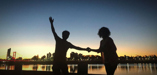 Silhouette people standing against clear sky during sunset