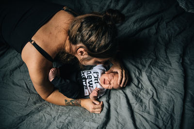 High angle view of mother looking at cute son sleeping on bed