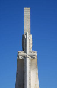 Low angle view of cross against building against clear blue sky