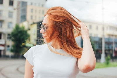 Woman with hand in hair standing in city