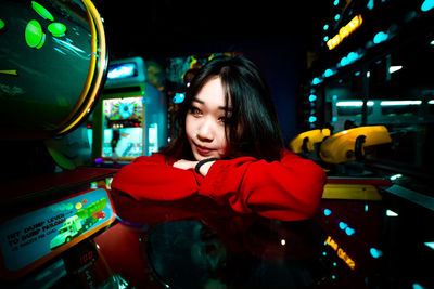 Portrait of woman looking at illuminated shop