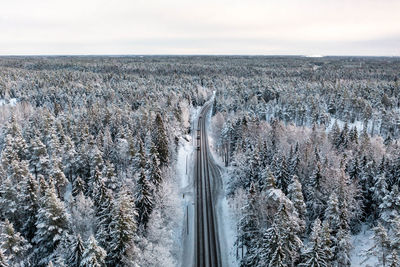 Frozen forest and cars on a road during winter from drone perspective, luukki espoo, vihti, finland