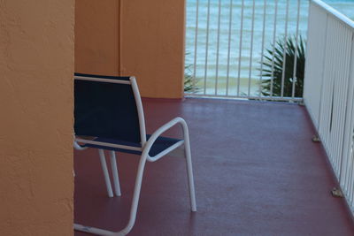 Empty chairs and table against window of building