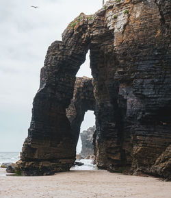 Rock formation on beach against sky