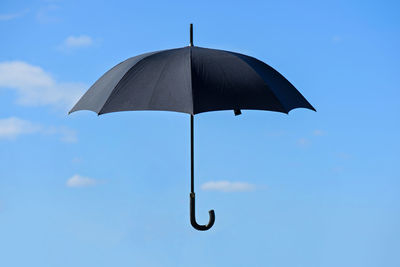 Low angle view of silhouette umbrella against blue sky