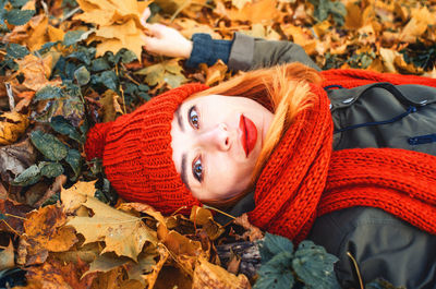 Happy woman with red hair and black eyes enjoying nature in autumn forest. close-up portrait of girl