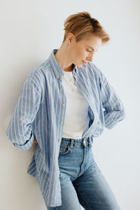 Woman in a blue shirt with short hair poses. brooding millennial woman in a white studio