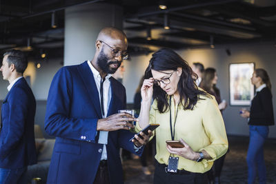 Male entrepreneur showing smart phone to female colleague in office