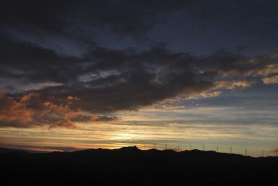 Silhouette landscape against dramatic sky during sunset