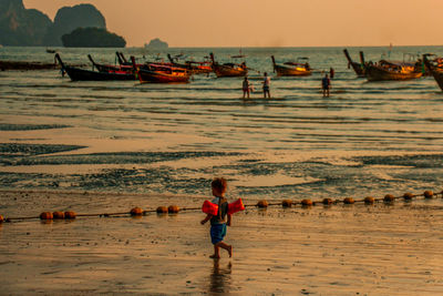 Boy on beach against sky during sunset