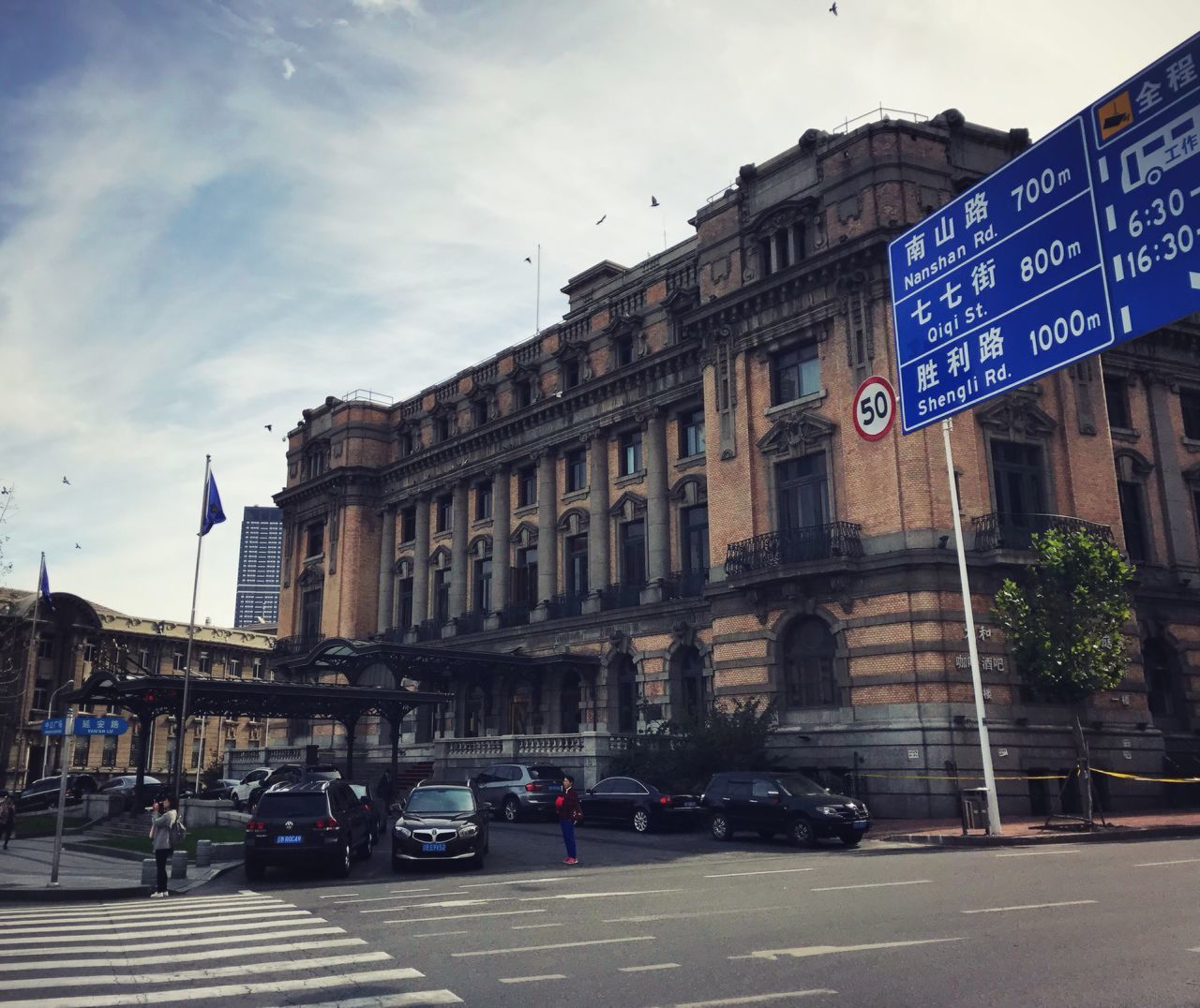 architecture, car, building exterior, built structure, sky, land vehicle, transportation, street, day, mode of transport, text, communication, road, outdoors, city, cloud - sky, road sign, no people